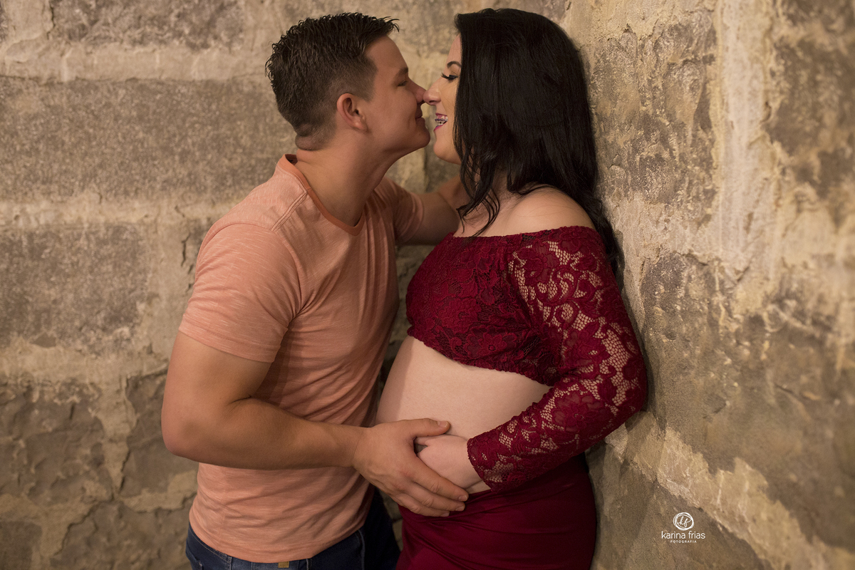 no ensaio de gestante o pai beija a esposa