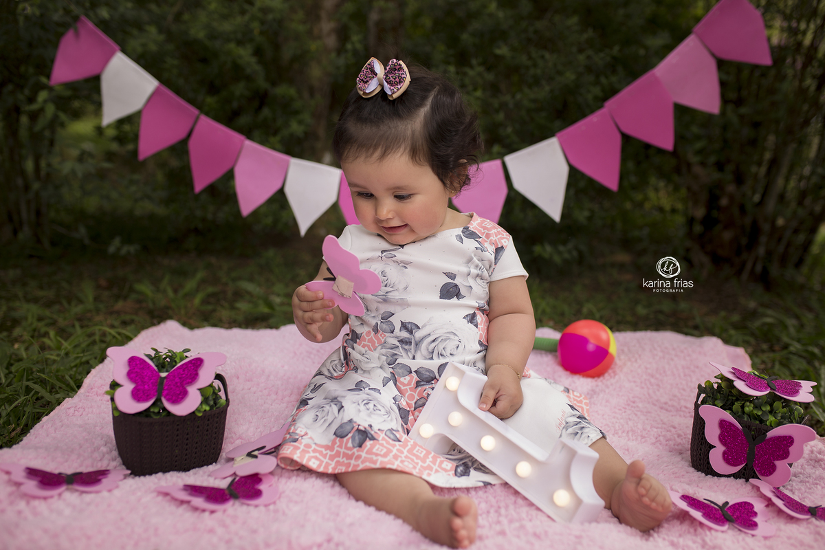 a menina olha para a borboleta no ensaio infantil