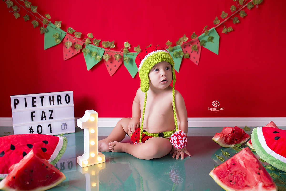 o menino esta sentado no cenario do smash de melancia