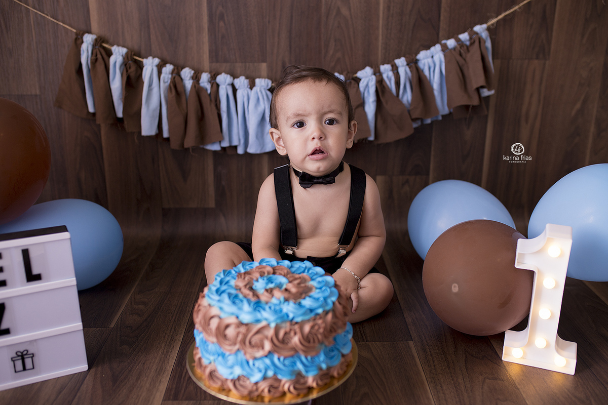 o bebe esta sentado em frente ao bolo para o ensaio
