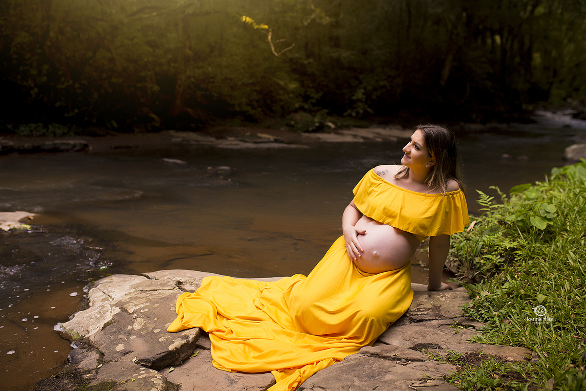 a gestante esta sentada na beira do rio