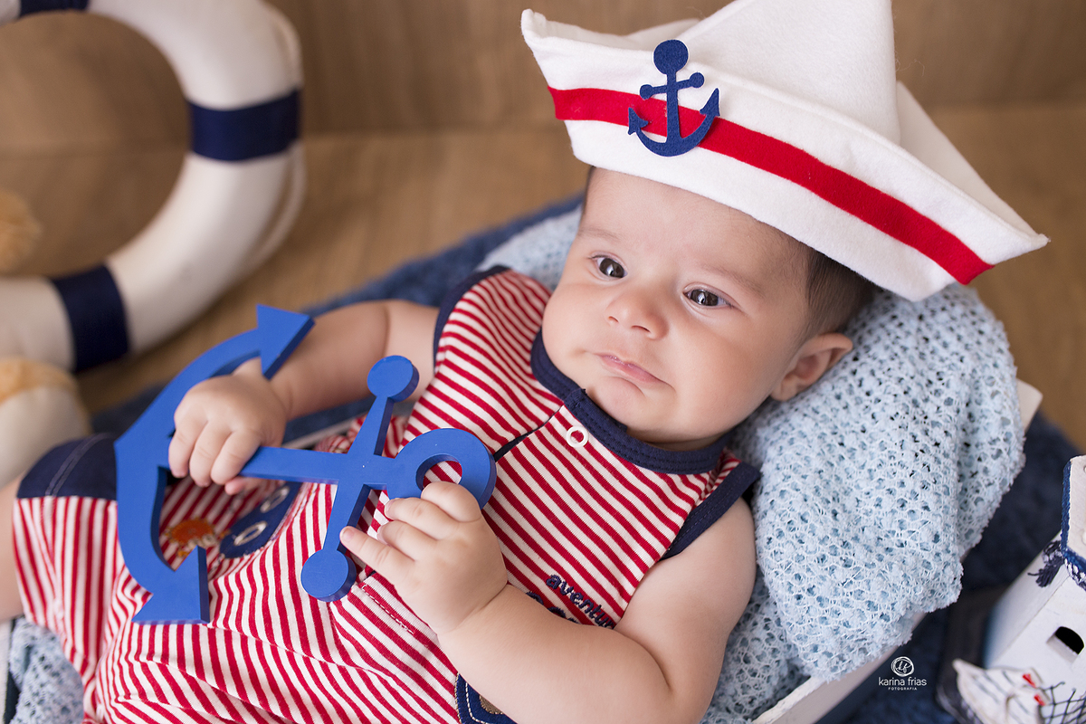 o menino segura a ancora enquanto a fotografa de bebes de caxias do sul registra o momento