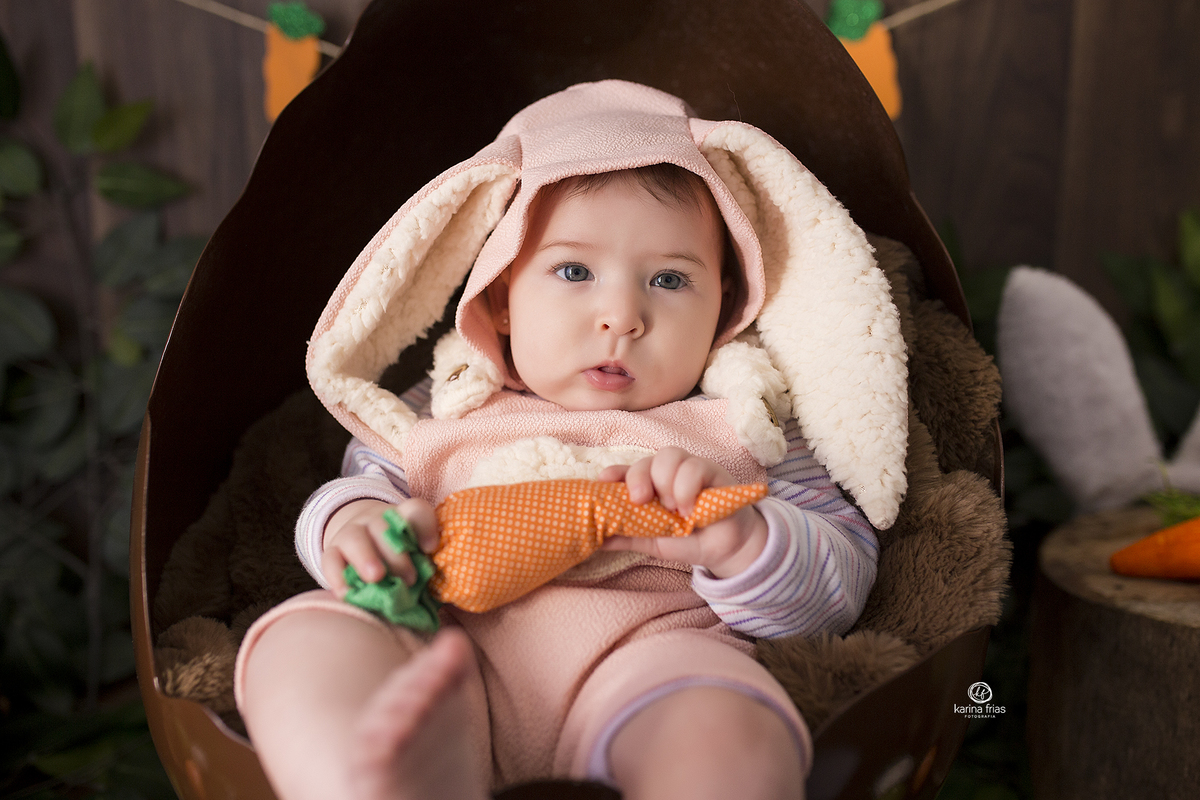 a menina esta deitada dentro do ovo para as fotos mensais