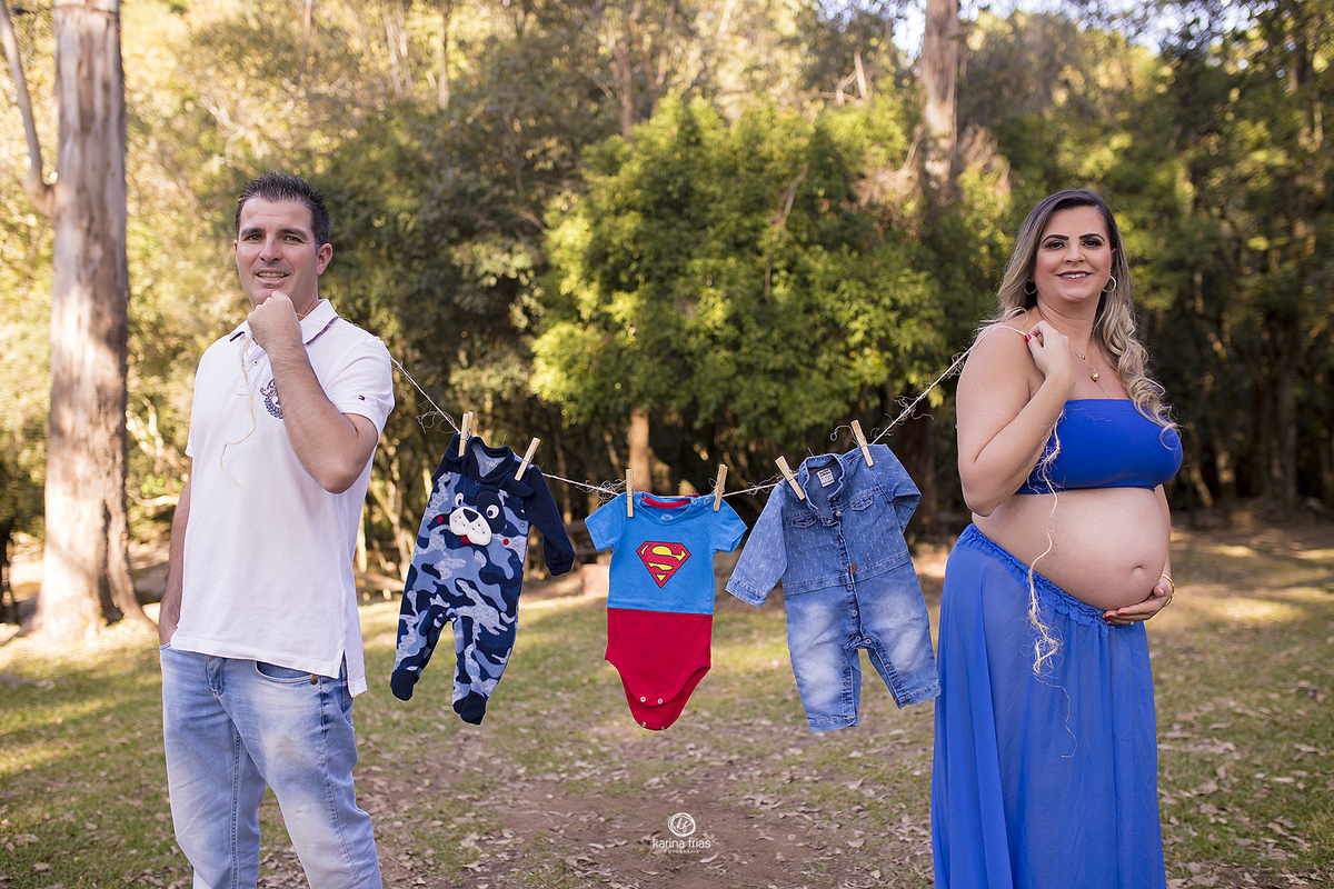 os pais seguram as roupinhas do bebe no ensaio de gestante