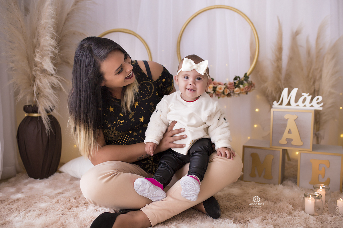 a menina esta sentada no colo da mae para as fotos mensais