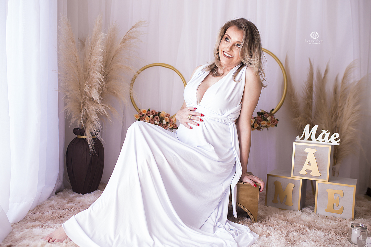 a mae senta no banco para as fotos de gestante