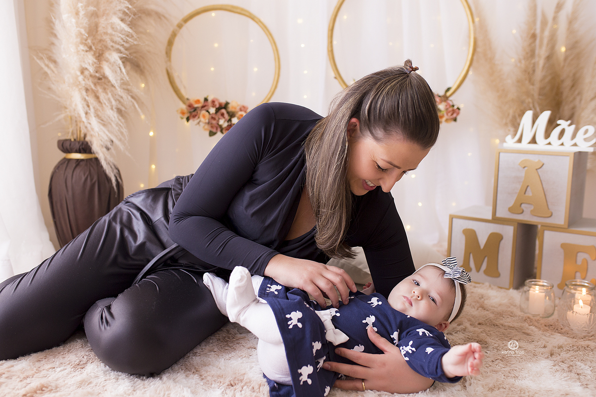 a mae brinca com a filha no ensaio de acompanhamento mensal