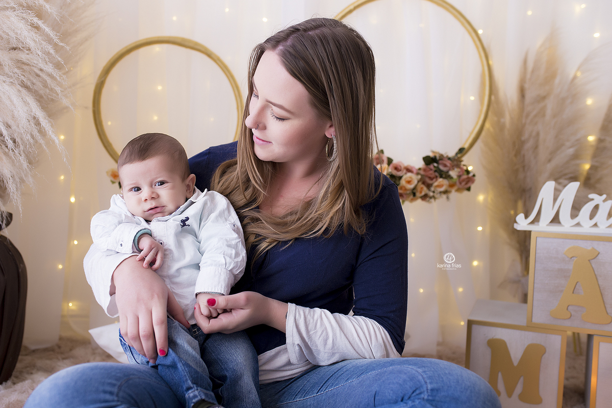 o filho esta no colo da mae para as fotos mensais