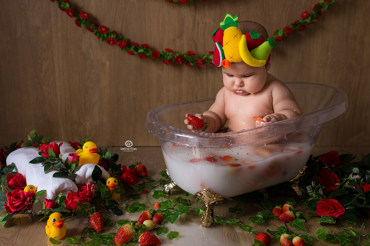 no ensaio infantil, a bebe olha os morangos na agua