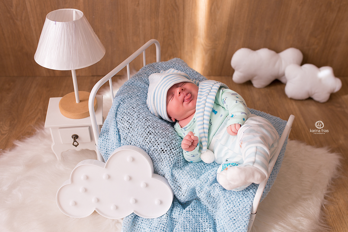 o menino esta deitado no cenario de quarto para as fotos do seu primeiro mês