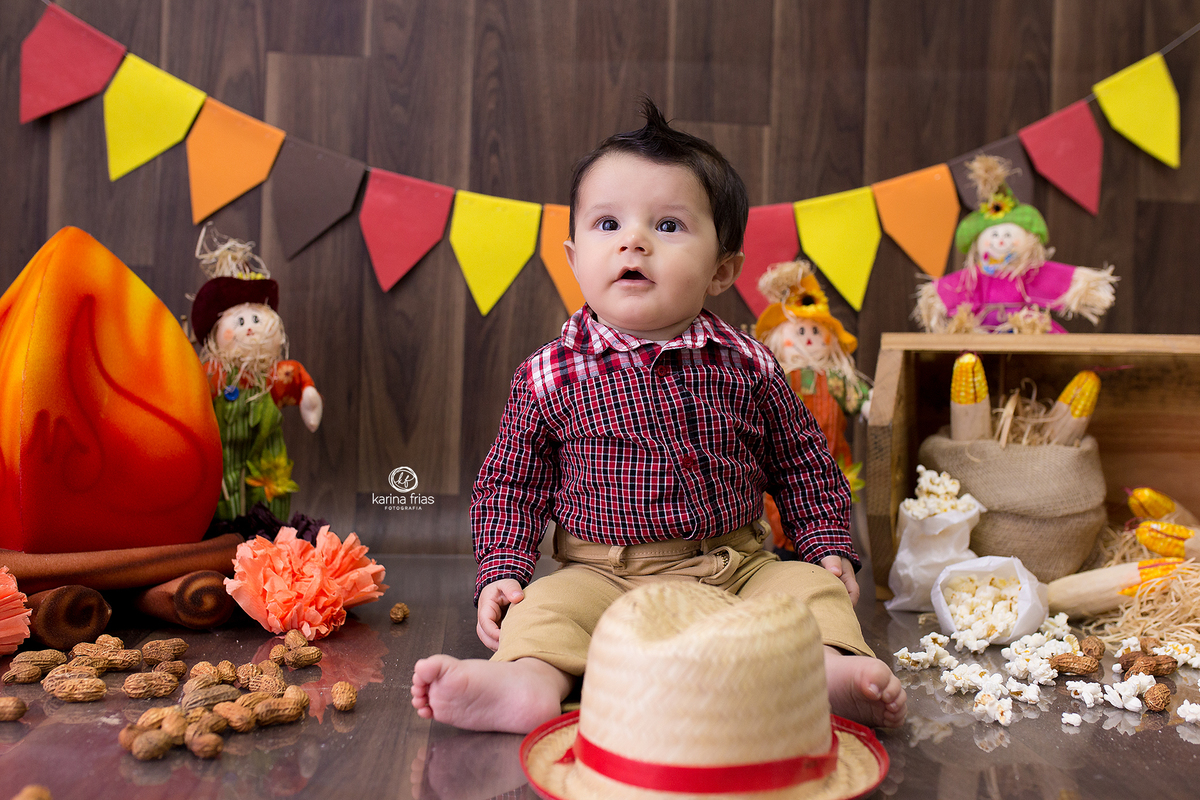 o menino esta sentado no cenario de festa junina