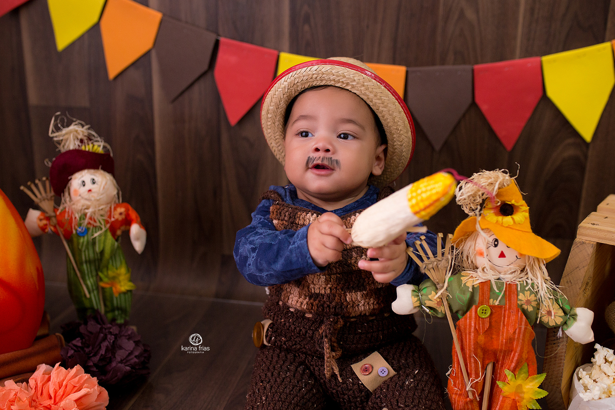 O bebe brinca com o milho no ensaio infantil
