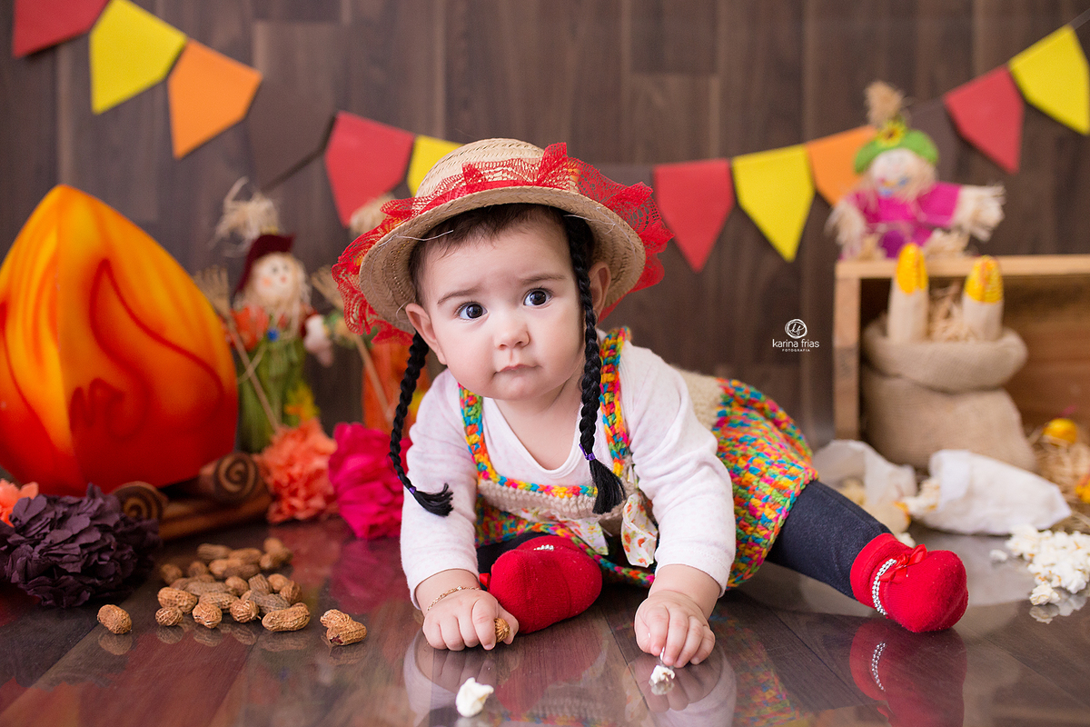A bebe brinca com as pipocas do cenario junino
