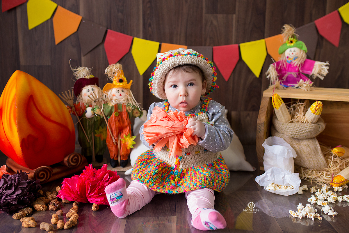 a menina esta sentada no cenario de festa junina