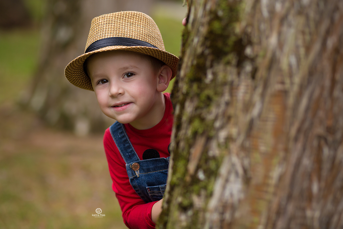 o menino espia atras da arvore no ensaio de 4 anos