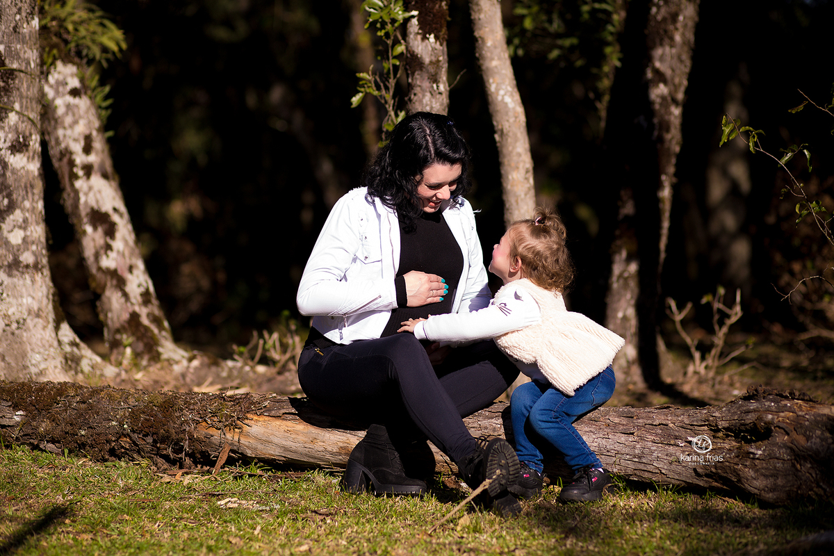 mae e filha brincam durante ensaio externo de gestante