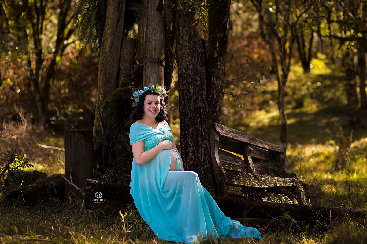 no ensaio de gestante a modelo esta sentada em um tronco