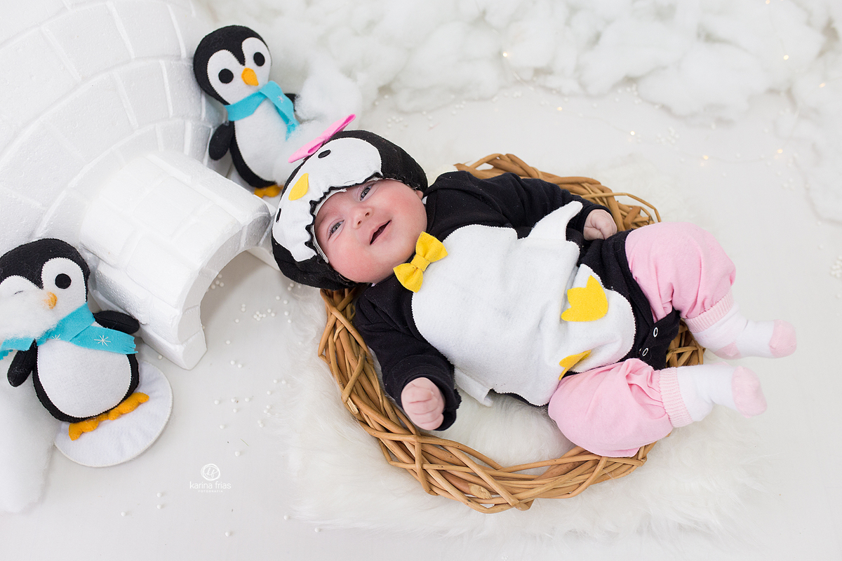 a bebe esta vestida de pinguim para as fotos do acompanhamento mensal