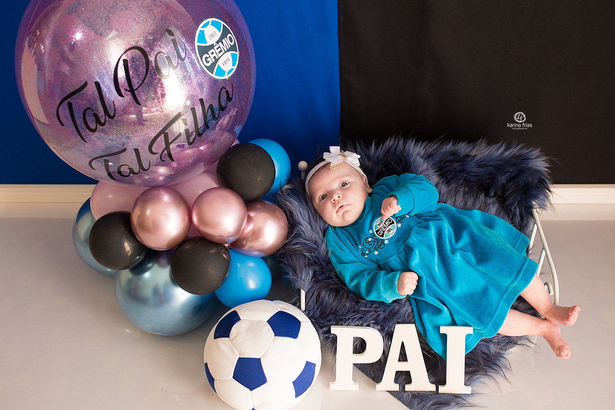 A BEBE ESTA DEITADA NO CENARIO DE GREMIO PARA AS FOTOS DE DIA DOS PAIS