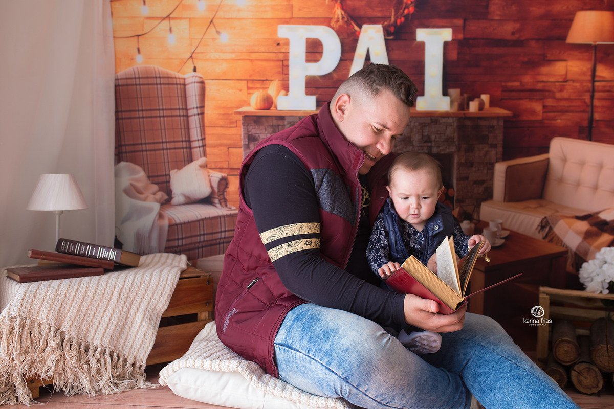 o pai le para o filho segurando-o no colo durante sessão infantil em caxias do sul-rs