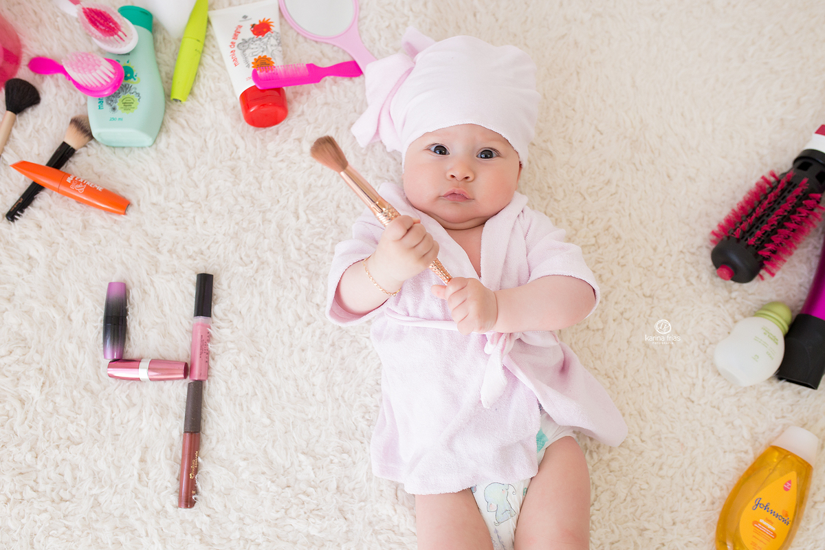 a bebe segura o pincel nas suas fotos de acompanhamento mensal