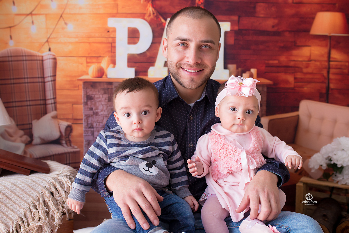 as crianças estao sentadas no colo do pai para as fotos mensais