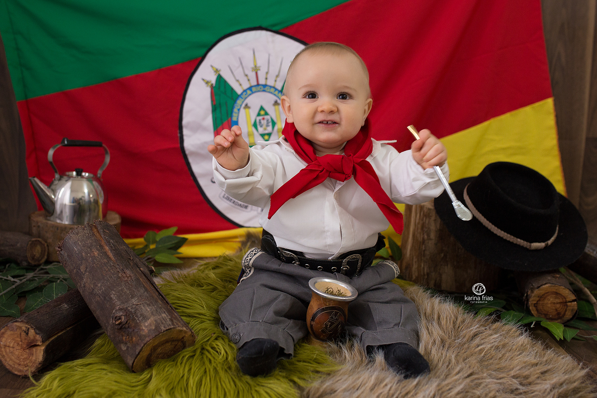 o menino esta vestido de gaucho para suas fotos mensais