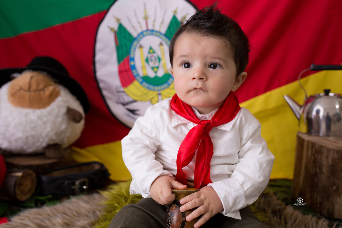o menino esta vestido de gaucho para as fotos mensais