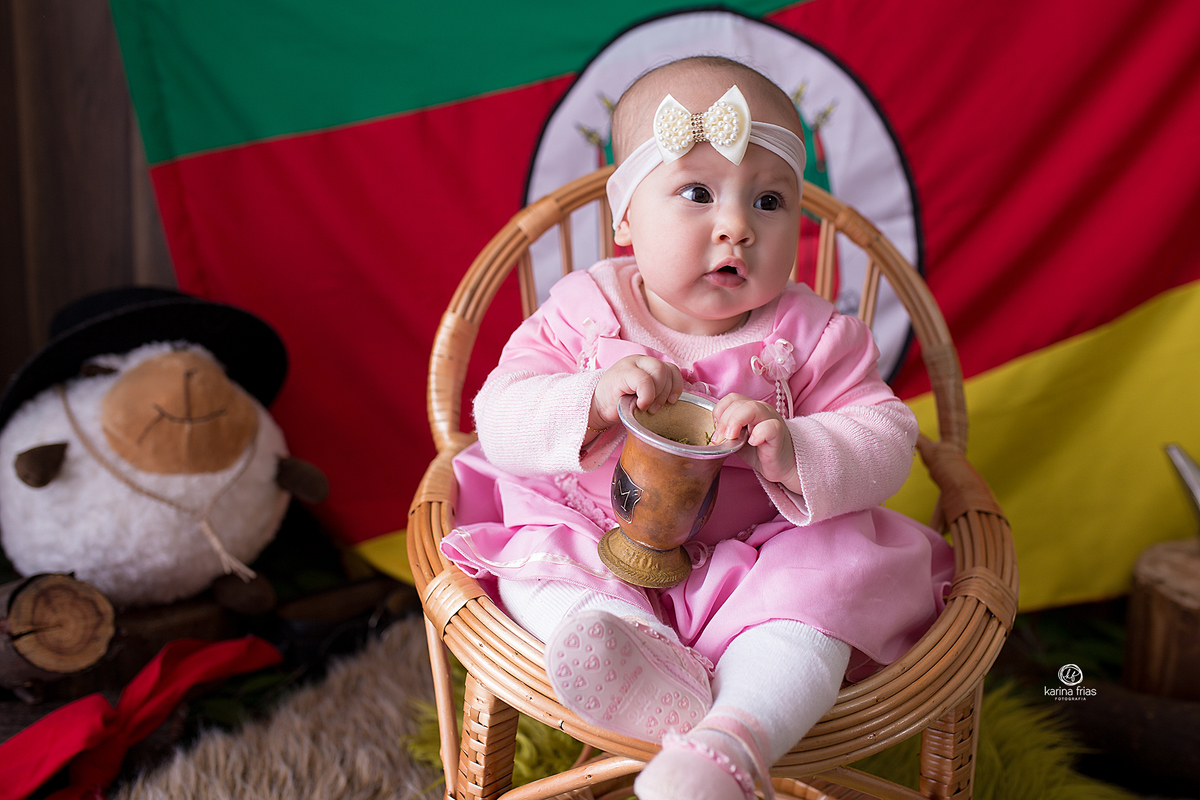 a bebe segura a cuia do chimarrao durante ensaio infantil