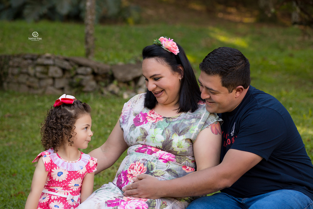 os pais olham para a filha mais velha na sessão de gestante