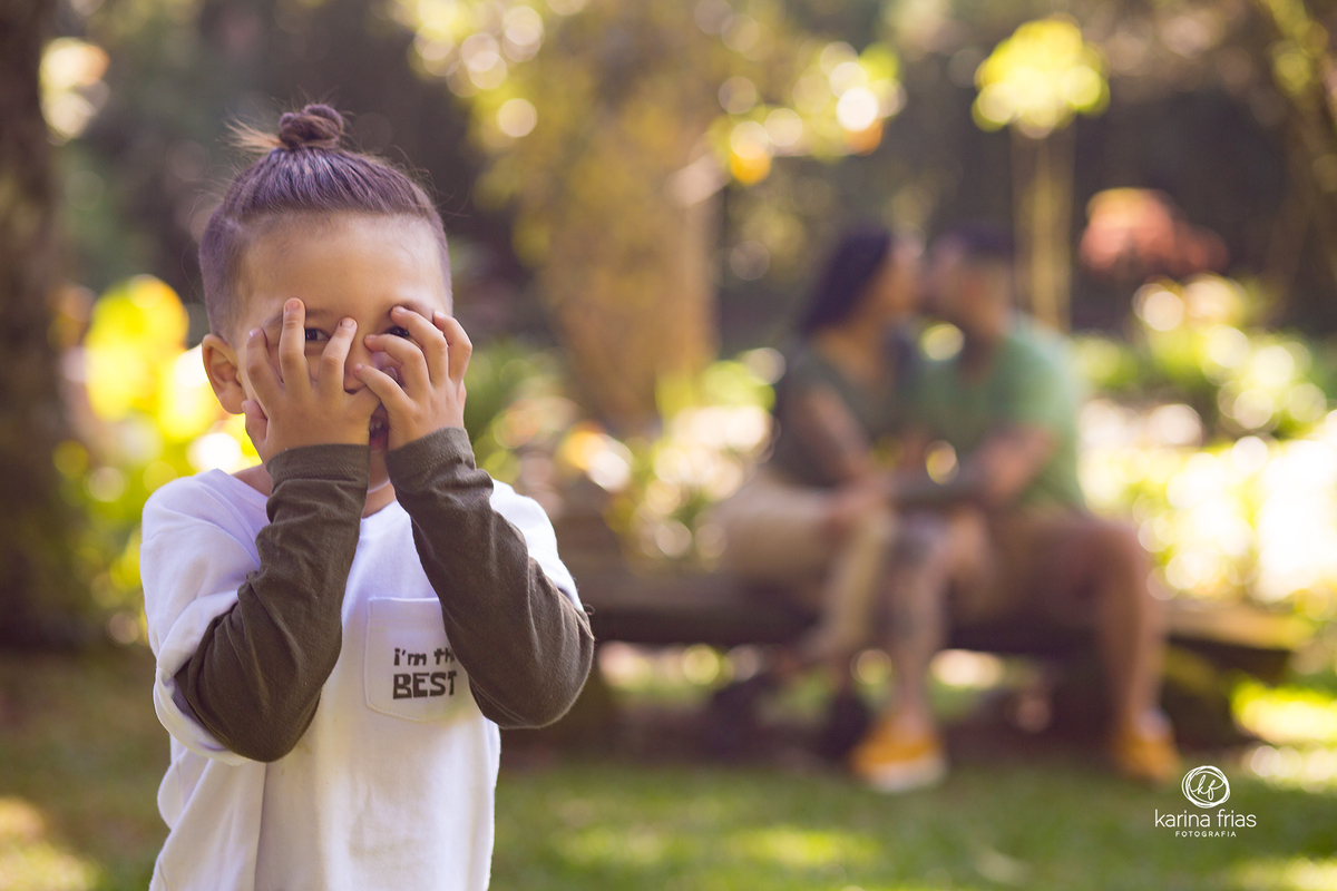 o menino sorri enquanto os pais estao ao fundo