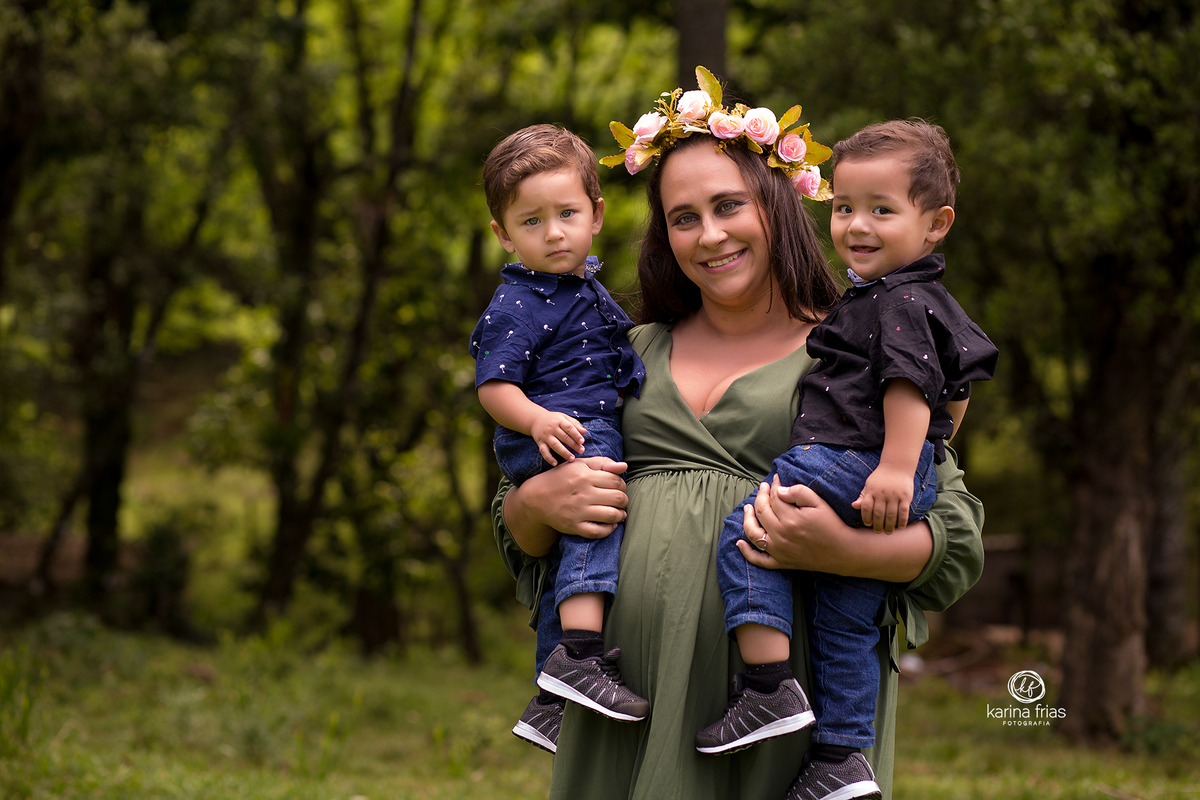 os gemeos estao no colo da gestante para a sessão de fotos