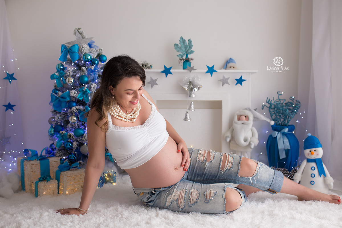 a gestante olha para a barriga durante sessão de fotos