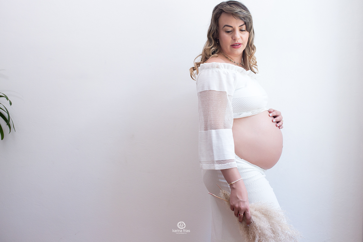 a gestante segura o ramo nas suas fotos de gestação