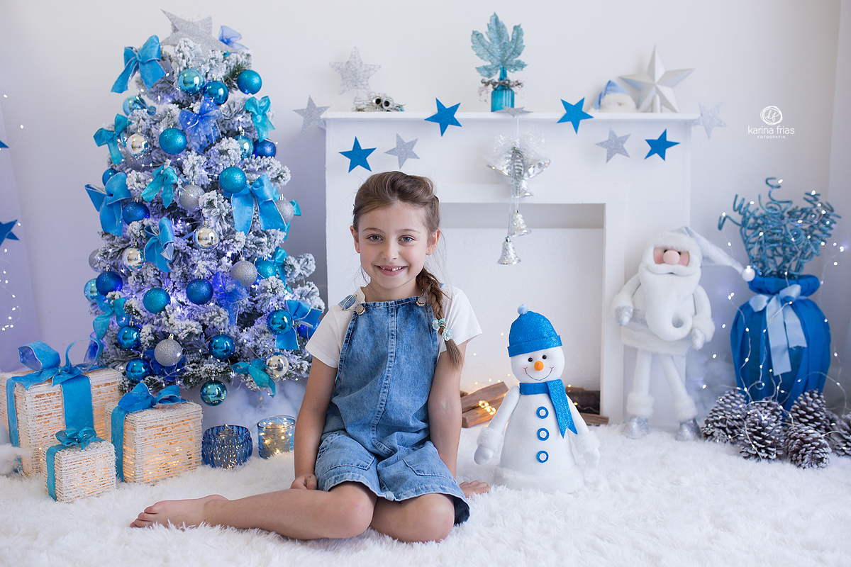 A menina esta sentada no cenario de natal