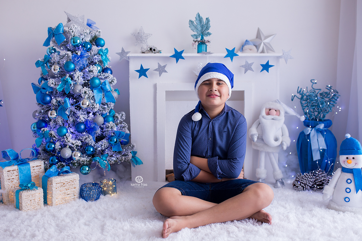 O menino esta sentado no cenario de natal