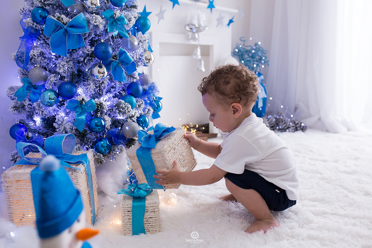 a criança brinca com os presentes na sessão de natal