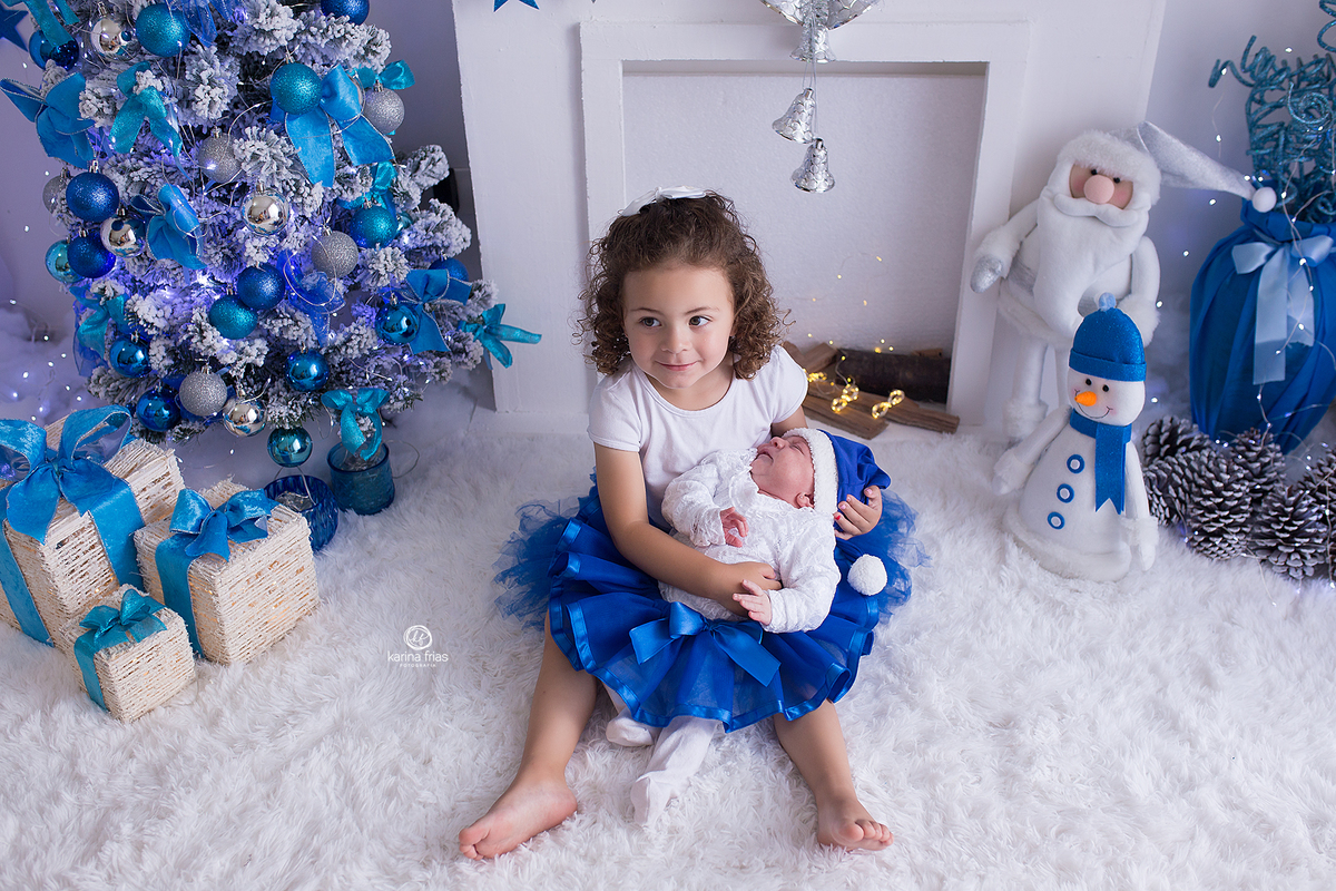 a irma mais velha segura a bebe para as fotos mensais