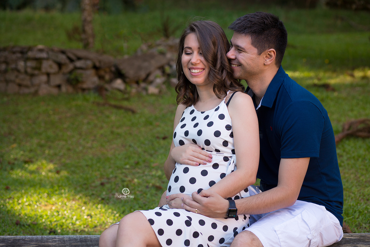 o casal sorri no ensaio de gestante externo