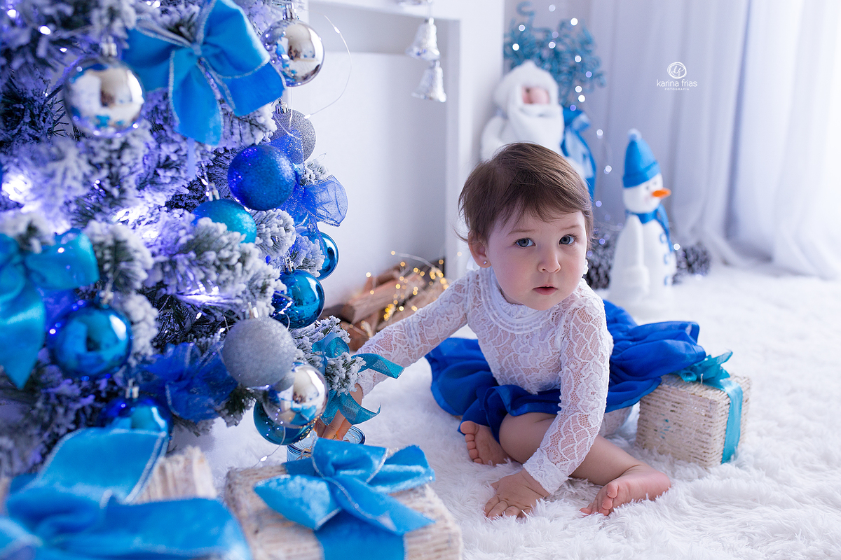 a menina mexe na arvore de natal durante sessão de fotos