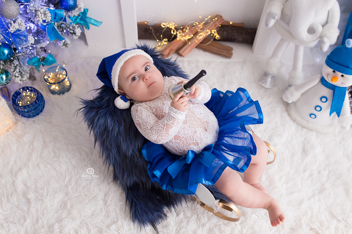 a bebe segura o sino na sessão de natal