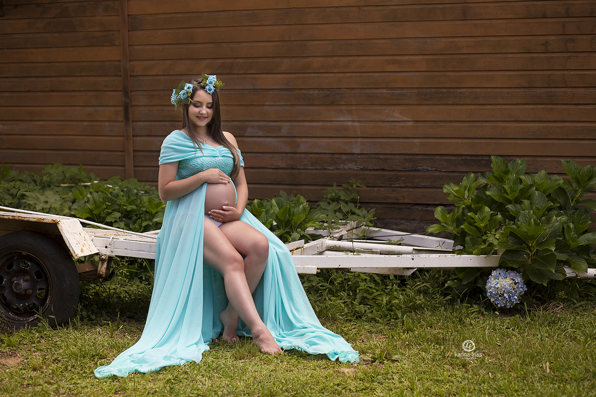 amodelo esta sentada enquanto a fotografa de gestante de caxias do sul, clica o momento