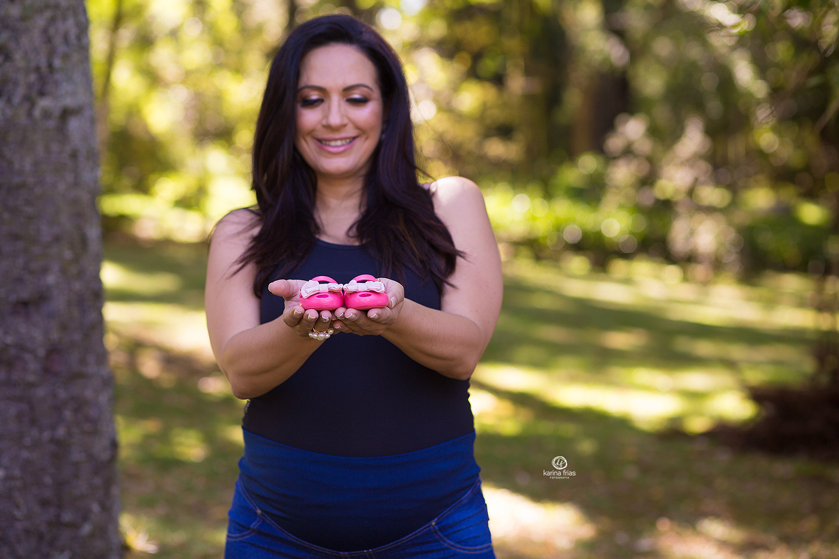 a gestante mostra o sapatinho da bebe na sessão de fotos