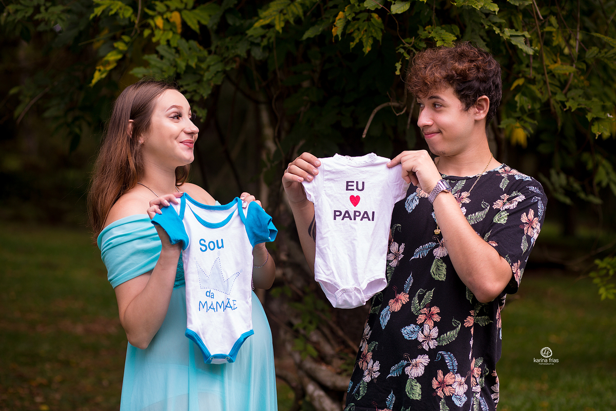 os pais brincam com as roupinhas da bebe no ensaio externo de gestante em caxias do sul-rs