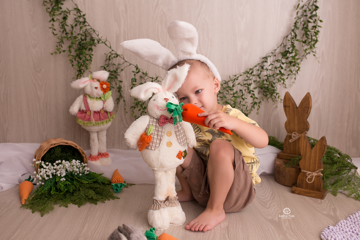 o menino brinca com o coelho na sessão de fotos