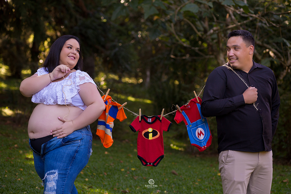 os pais seguram o varal com as roupas do bebe no ensaio