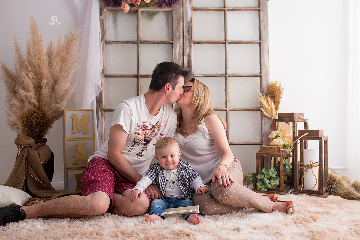 os pais se beijam no ensaio e o bebe sorri