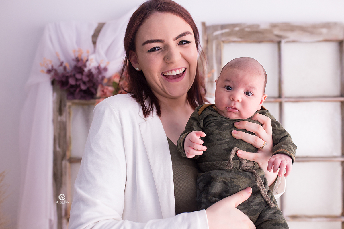 o menino esta no colo da mae para as fotos mensais
