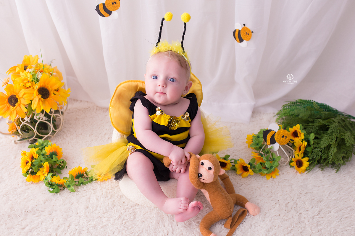 a bebe segura o macaco na sessão de abelhinha