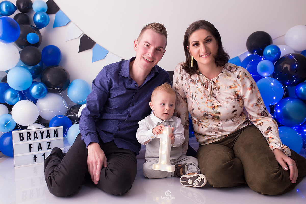 os pais posam com a criança no cenario de baloes